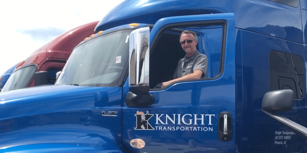 Driver standing in the door of his truck showing Knight Transportation logo