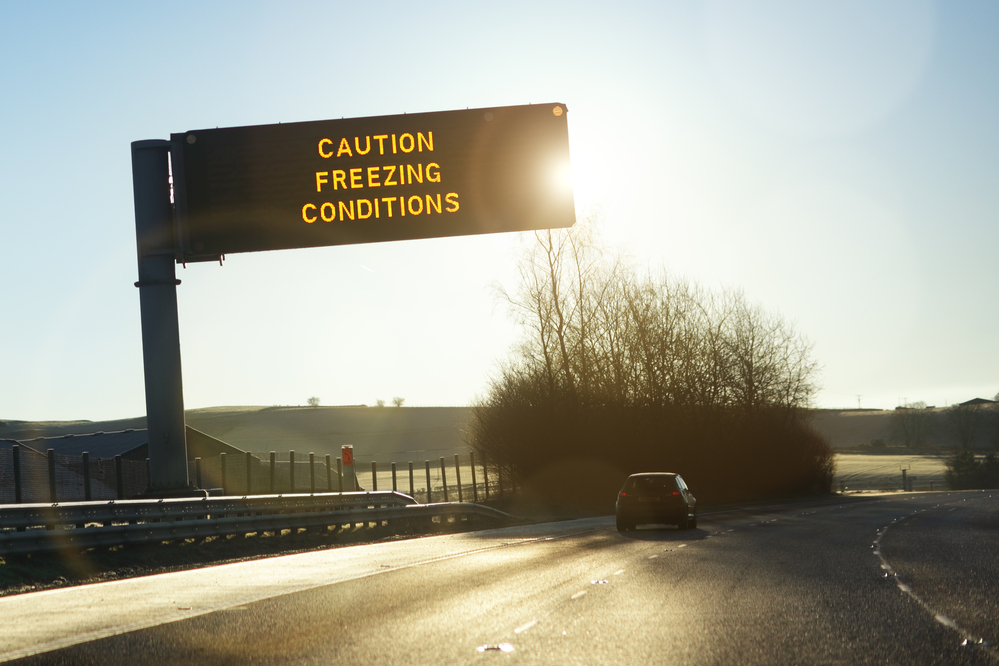 Winter traffic sign reading "caution freezing conditions" 